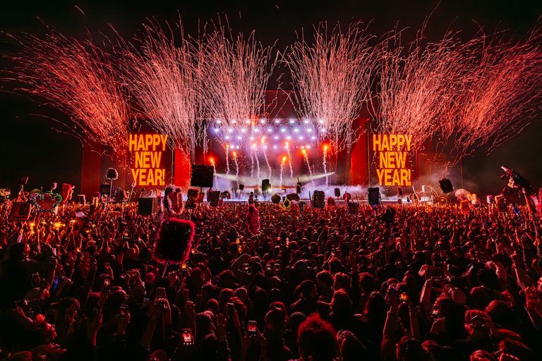 Crowd cheering as streamer cannons burst over stage reading Happy New Year during Midnight at Beyond The Valley music festival in Victoria Australia.